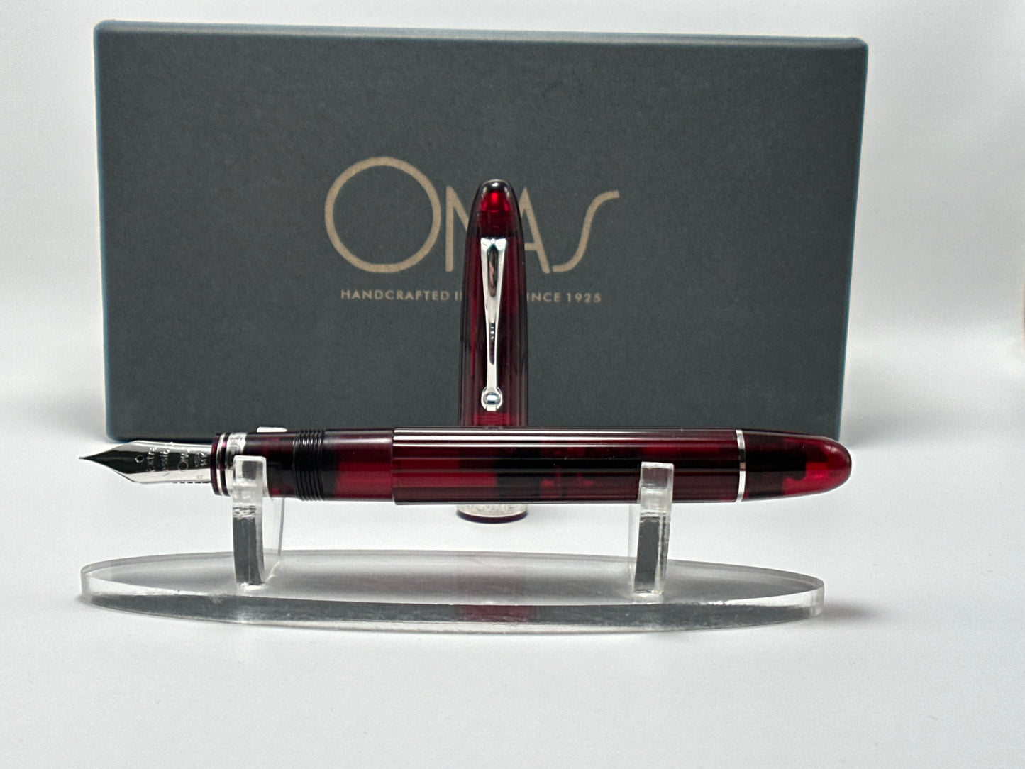 Red and black fountain pen on a stand with a gray box featuring 'Orvar' branding in the background.