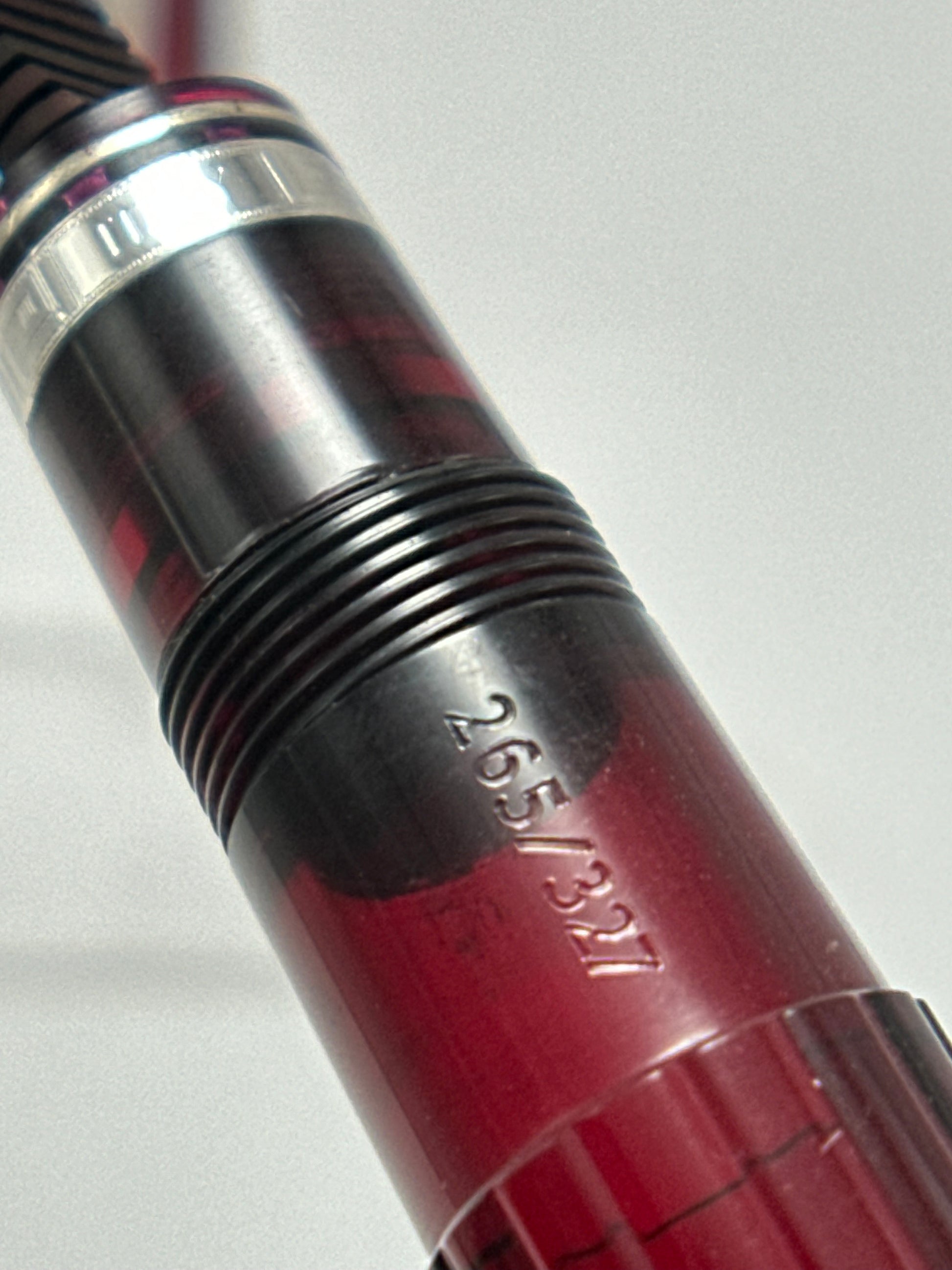 Close-up of a red and silver fishing rod handle with measurement markings on a white background