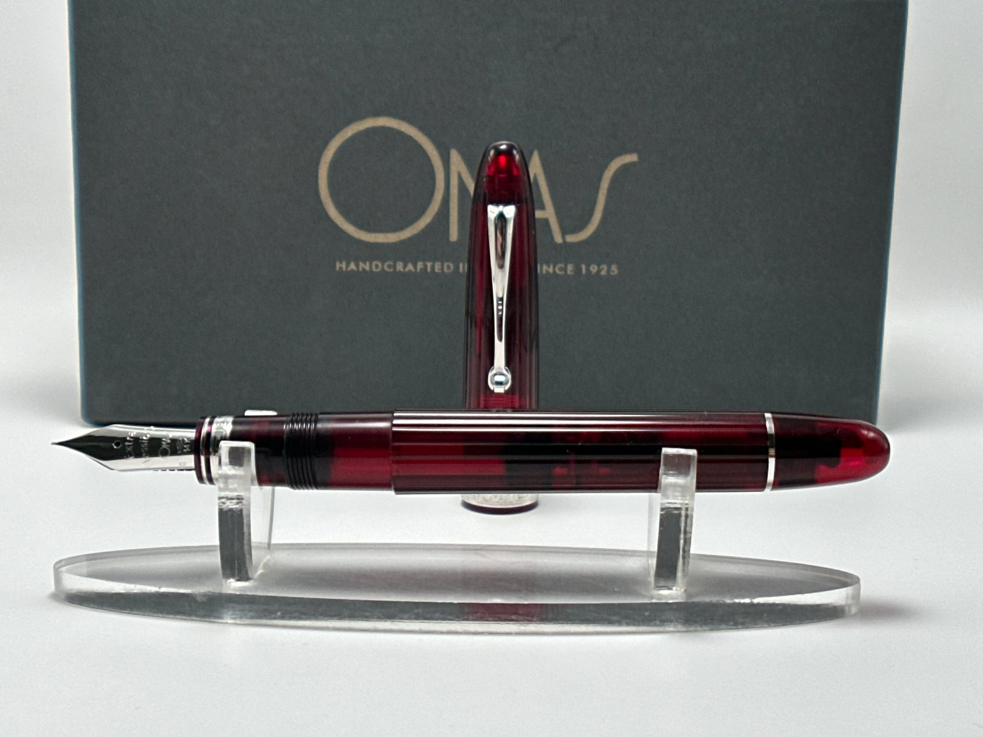 Red and black fountain pen on a stand with a gray box featuring 'Orvar' branding in the background.